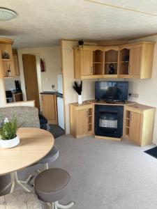 a living room with a couch and a tv and a table at Spacious 8 Berth Caravan in Ingoldmells in Ingoldmells