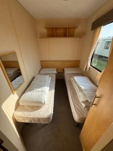 a small room with two beds and a window at Spacious 8 Berth Caravan in Ingoldmells in Ingoldmells