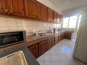 a kitchen with wooden cabinets and a sink and a microwave at Maarif Central Stay 2 in Maarif
