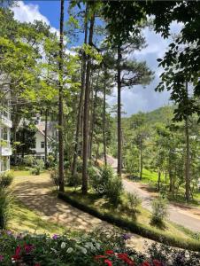 a garden with trees and flowers in front of a house at Lan anh Village - Luxury villa Tuyen lam lake view in Xuan An