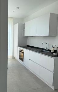 Una cocina con gabinetes blancos y un fregadero. en Appartamento VINESSA - Residence OLIVEA, en Riva del Garda