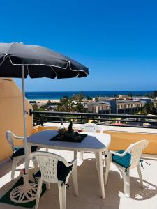 a table and chairs on a balcony with an umbrella at Las Mareas Sea View Terrace 3 min to Beach in Morro del Jable