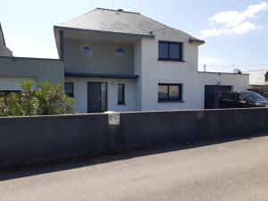 a white house with a black fence in front of it at VILLA SPACIEUSE en bord de mer in Ploemeur