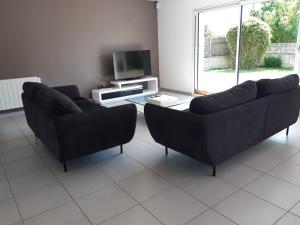 a living room with two couches and a tv at VILLA SPACIEUSE en bord de mer in Ploemeur