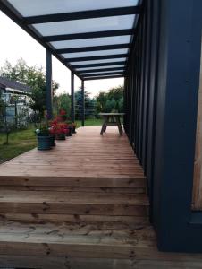 a wooden porch with a picnic table and potted plants at Namelis soduose in Akademija +1 photo