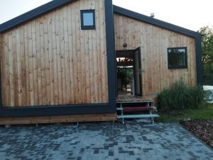 a timber clad house with a bench in front of it at Namelis soduose in Akademija