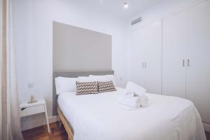 a white bedroom with a large white bed with towels on it at Eclectic 2BR with shared terrace perfect getaway in Gibraltar