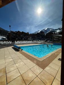 a large swimming pool with mountains in the background at L'écrin des Orres 1800, appartement 5 à 7 personnes avec parking privé in Les Orres