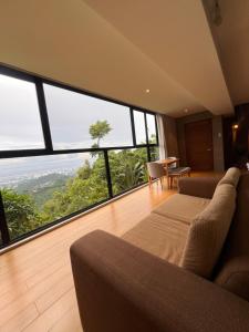 ein Wohnzimmer mit Sofa und großen Fenstern in der Unterkunft Busay Getaway in Cebu City