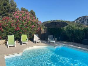 a swimming pool with two chairs and an umbrella at Mas provençal avec piscine privée proche Bandol in Évenos