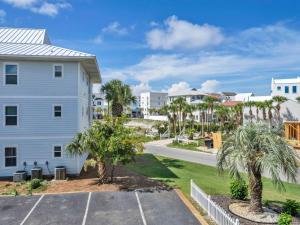 a house with palm trees next to a street at Beachside Villas 122- Sun for the Roses in Santa Rosa Beach