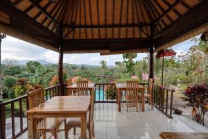 a patio with tables and chairs on a balcony at Kampuak Cottages in Nusa Penida