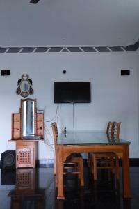 mesa de comedor con sillas y TV de pantalla plana en Munnar Mountain view cottage, en Munnar