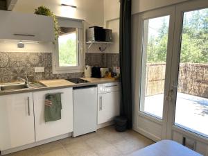 a kitchen with white cabinets and a sink and a window at Charming studio in an exceptional equestrian farm in Camps-la-Source