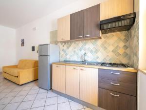a kitchen with wooden cabinets and a refrigerator at Belvilla by OYO Conca degli Dei con giardino in Paestum