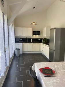 a kitchen with a table and a stainless steel refrigerator at Gîte des Petites Fadettes "MELUSINE" in Lannepax