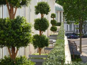 a row of trees and benches next to a building at Hotel Xenia, Autograph Collection in London