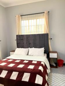 a bed with a red and white striped blanket and a window at Sinana Escapes - Arusha in Arusha