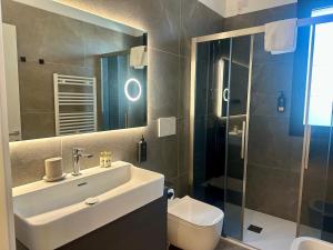a bathroom with a sink and a toilet and a mirror at Caribe Sunset - Large 3 Bedrooms with Caribbean Pool in Lido di Jesolo