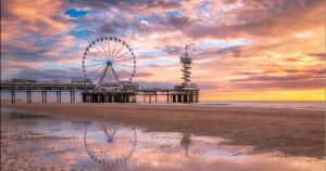 a ferris wheel on the beach at sunset at Apartment by the Beach in Scheveningen