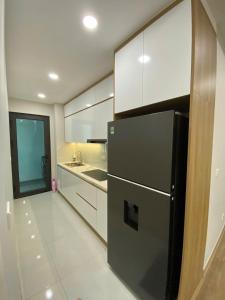 Una cocina con refrigerador negro y gabinetes blancos. en HomeStay Old Quarter Hai Phong, en Hai Phong 2 fotos más