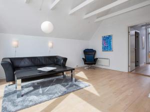a living room with a black leather couch and a chair at 6 person holiday home in Væggerløse-By Traum in Marielyst