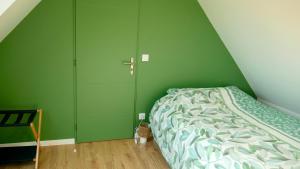 una camera da letto verde con un letto e un armadio di Maison des Hirondelles a Yvré-lʼÉvêque