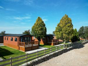 una fila de cabañas con árboles y una valla en Wild Rose Holiday Park, en Great Ormside
