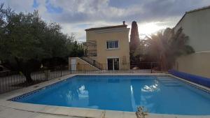 a villa with a swimming pool in front of a house at Les oliviers in Lédignan