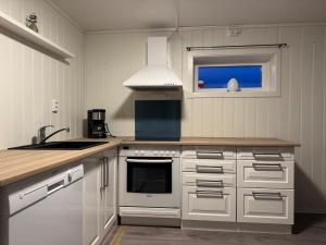 a kitchen with white cabinets and a stove top oven at Apartment in Tromsø in Tromsø +7 photos