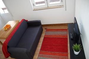 Sofá negro en una sala de estar con alfombra roja en Casa Das Gaivotas, en Sesimbra