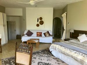 a bedroom with two beds and a table and a couch at Cycasia Lodge in Umzumbe