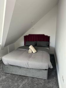 a bedroom with a bed with a red headboard at New 4-Bedroom Family Home with Free Parking in Bredbury +1 photo