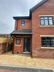 a red brick house with a black roof at New 4-Bedroom Family Home with Free Parking in Bredbury