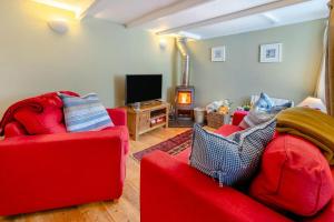 ein Wohnzimmer mit zwei roten Sofas und einem TV in der Unterkunft Smugglers Cottage in Porthleven