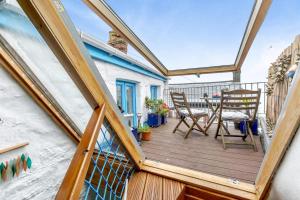 eine Holzterrasse mit einem Tisch und Stühlen auf dem Balkon in der Unterkunft Smugglers Cottage in Porthleven