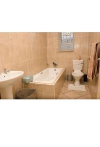 a bathroom with a tub and a toilet and a sink at Mbuso Guest House in Richards Bay