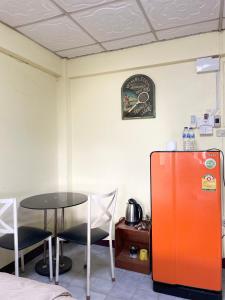 an orange refrigerator and a table in a room at Haiya Guesthouse room 9 in Chiang Mai