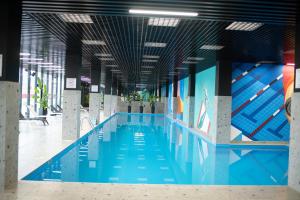 a large swimming pool with blue water in a building at Batumi Skynest in Batumi