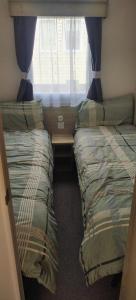 two beds in a small room with a window at Beach Haven in Berwick-Upon-Tweed