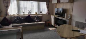 a living room with a couch and a television at Beach Haven at Berwick in Berwick-Upon-Tweed