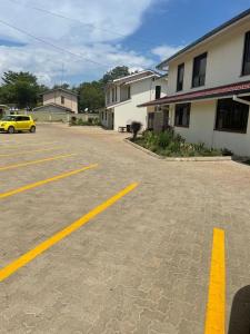 a parking lot with a yellow car parked next to a building at Home Haven- 3 Bedroom Apartment in Kisumu