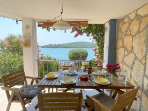 a wooden table with chairs and a view of the water at Small house at seafront in Tisno