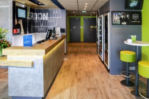 an office lobby with a reception desk and yellow stools at ibis Budget Hotel Vitrolles in Vitrolles