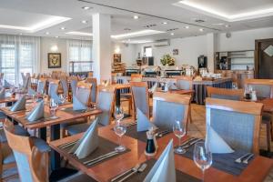a restaurant with wooden tables and chairs with wine glasses at Budapest Airport Hotel Stáció Wellness & Konferencia in Vecsés