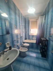 a blue tiled bathroom with a sink and a toilet at Casa vacanza Nicla in Rosolini