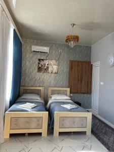 ein Schlafzimmer mit zwei Betten und einem Gemälde an der Wand in der Unterkunft Chelo Guest House in Kutaissi