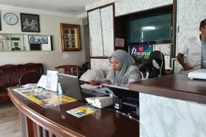 a woman sitting at a counter with a laptop at Persona Boutique Hotel in Malacca