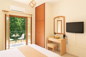 a bedroom with a bed and a television and a balcony at Artemida Pansion Georgioupolis in Kournás