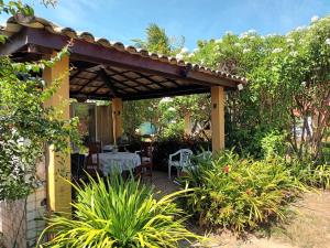 a pergola with a table and chairs in a garden at Lumiar Garden Suítes e Chalés em Vilas do Atlântico in Lauro de Freitas